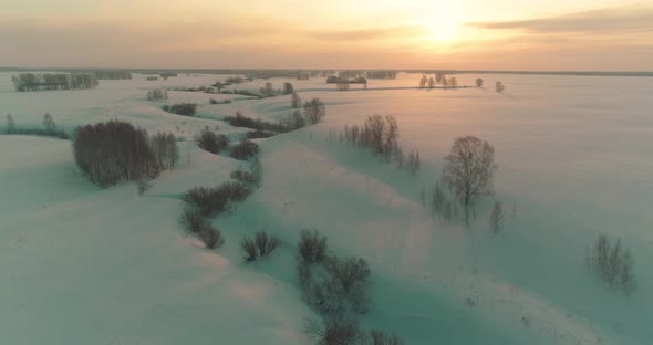 Aerial View of Cold Arctic Field Landscape Trees with Frost Snow Ice River and Sun Rays Over Horizon