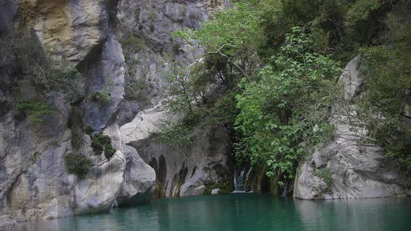 A Lake Surrounded By Rocks and a Small Waterfall