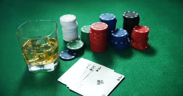 Playing cards, casino chips, bundle of us dollar and glass of beer on poker table 4k