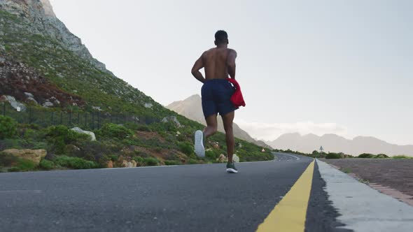 African american man exercising outdoors running on a coastal road