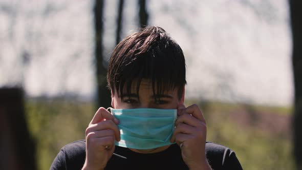 Close Up of Young Caucasian Man Taking on Medical Mask Outdoor. Sick Guy Wearing Protection During