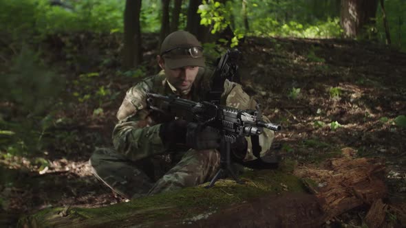 Military Man in Camouflage Reloading Machine Gun with Ammunition Box