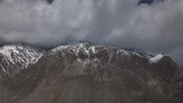 Ominous Clouds Above Peaks Of Snow Covered Mountains In Hunza, Pakistan. Aerial Slow Pan Left
