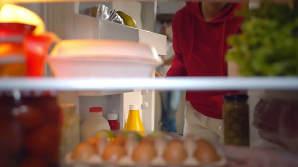 African Young Woman Looking For Food Inside Fridge In Kitchen