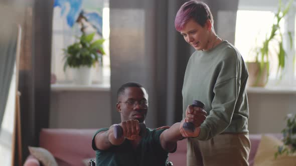 Woman Helping Disabled Man to Exercise with Dumbbells