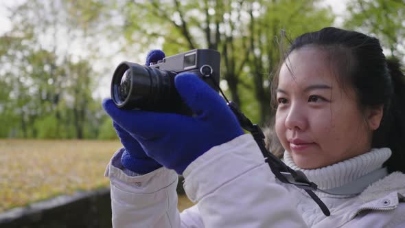 Close up Asian woman taking a photo of view at park in Autumn