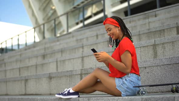 Mixed-Race Teenager Chatting With Friends in Social Networks and Smiling