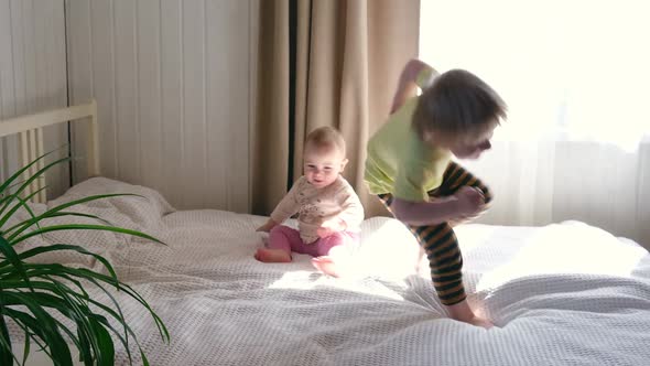 Two Happy Cheerful Little Children Brother and Sister Play Have Fun Jump on Bed