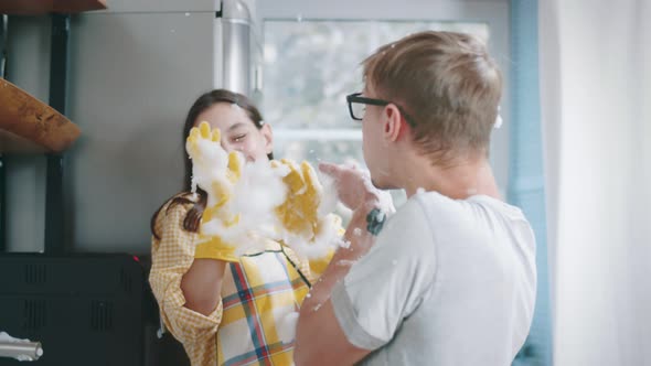 Close Up of Young Cheerful Couple in Love Playing and Playing with Foam Washing Dishes