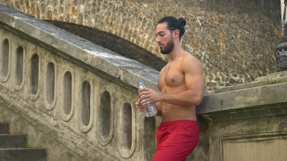 A man takes a break after a workout to drink water.