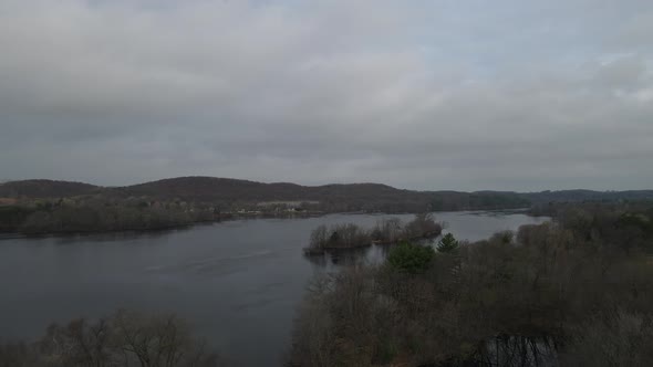 View over lake on a dark and stormy day. Mountains seen in the distance with forest, alt