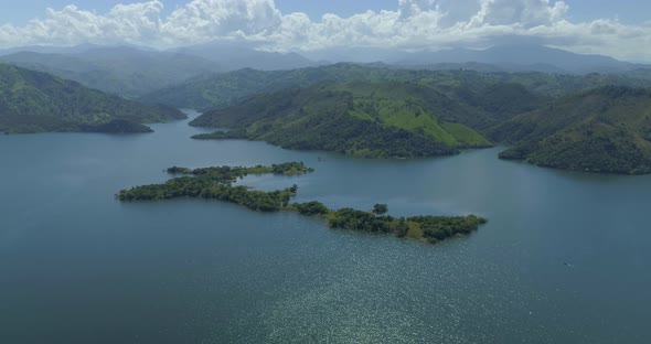 Beautiful lake by green hillside forest with Cordillera Central (Hispaniola) mountain range in backg