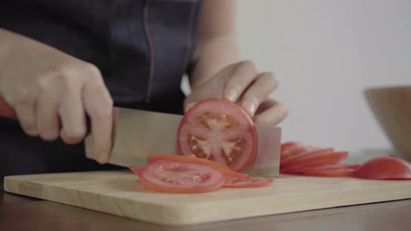 woman making salad healthy food and chopping tomato on cutting board in the kitchen.