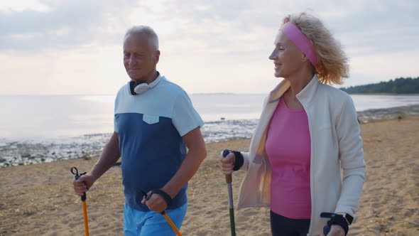 Happy Active Aged Couple Trekking Along Coastline on Sandy Beach in Morning