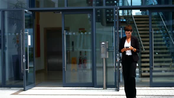 Businesswoman using mobile phone while walking