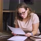 Woman is Sitting at Home at Table in Front of Laptop and Checks Documents Contract - VideoHive Item for Sale