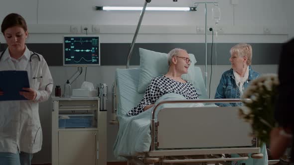 Aged Man Enjoying Visit From Daughter and Niece in Hospital Ward