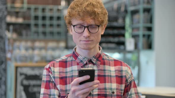 Attractive Young Redhead Man Using Smartphone