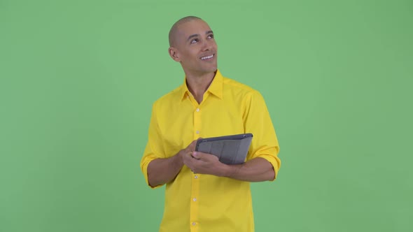 Happy Handsome Bald Businessman Thinking While Using Digital Tablet