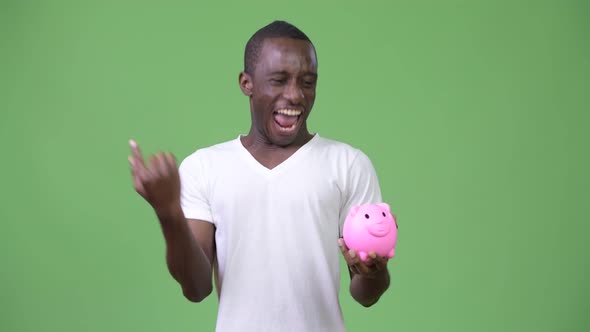 Young African Man Holding Piggy Bank and Giving Thumbs Up