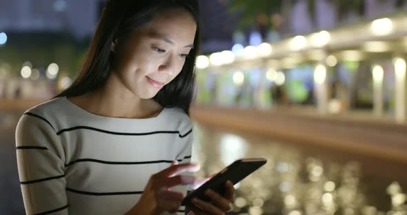 Woman looking at mobile phone in city at night