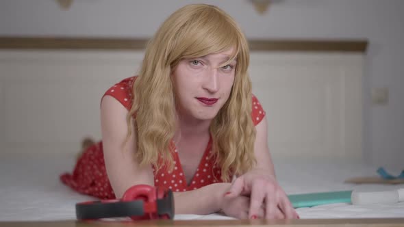 Positive Blond Caucasian Trans Woman Lying on Bed Looking at Camera Smiling