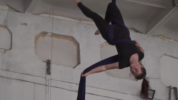 Acrobatic Training in the Gym Woman is Doing Aerial Silks Hanging Upside Down