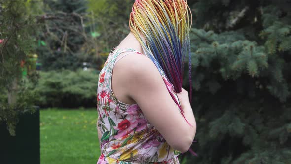 A Girl with a Happy Smile in a Dress with African Braids and Makeup Whirls and Throws Her Hair Up in