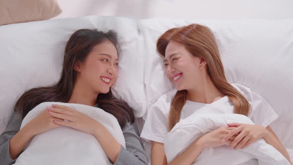 Beautiful asian young lesbian LGBTQ couple or friends lying on bed looking together smile and relax