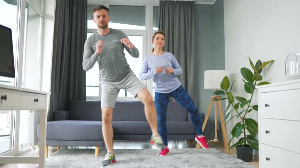 Caucasian Couple is Doing Squats and Kicks at Home in Cozy Bright Room Slow Motion