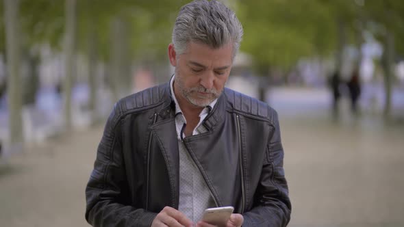 Excited Mature Man Using Smartphone Outdoor