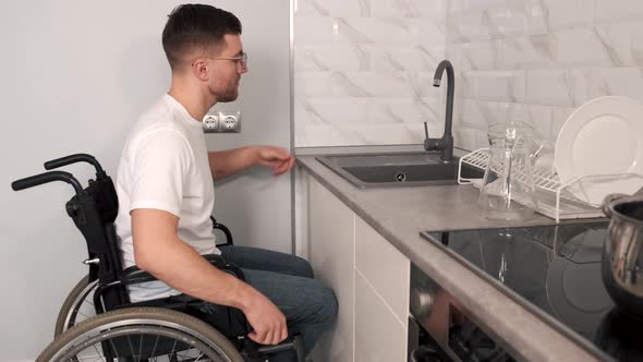 Young Happy Disabled Man On Wheelchair Washing Dishes