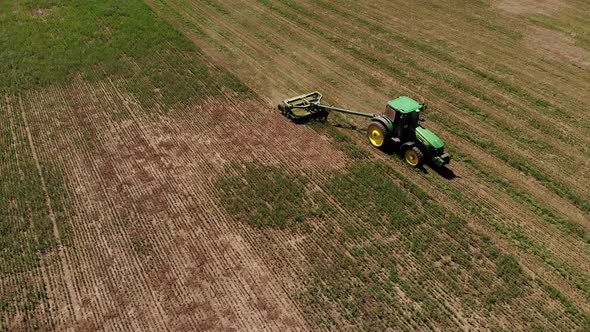Aerial View of a Tractor with a Mower Mows the Grass on an Empty Field