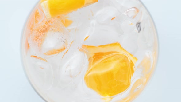 Overhead shot of a spinning glass of water with lemon and ice. Slow Motion.