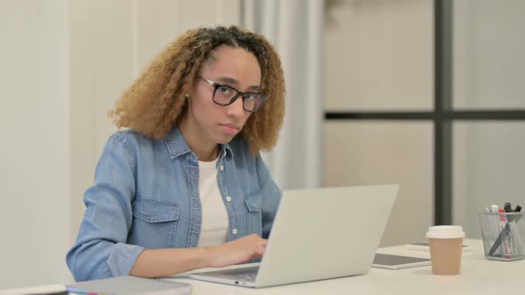 African Woman Showing Thumbs Down Sign While Using Laptop in Office