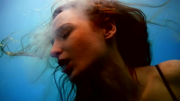 Enigmatic Woman is Breathing By White Smoke Inside Water Floating in Pool or Sea Closeup Portrait