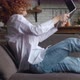 Side View of Excited Redhaired Young Woman Sits at on Sofa at Laptop Computer Working in Living Room - VideoHive Item for Sale