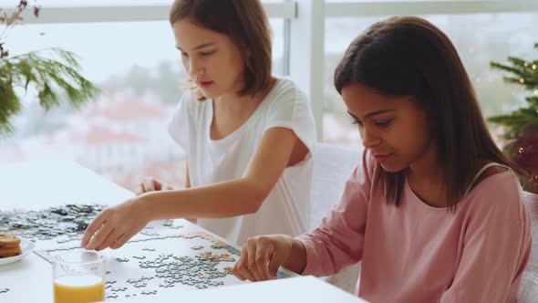 Two multiethnic sisters do jigsaw puzzles