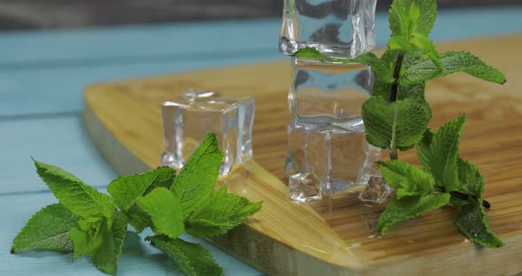 Ice Cubes and Mint Leaves Isolated on Wooden Cutting Board