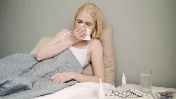 Young Sick Woman Sneezing at Home at Night on the Couch