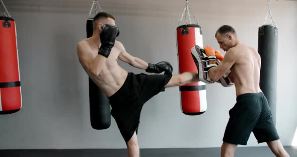 The Kickboxer is Practising His Knee Blow with Trainer in Slow Motion in the Gym Kickboxers are