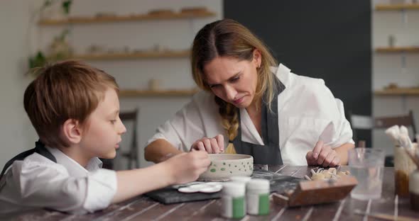 Child Boy with Mother Making Pattern on Clay Bowl