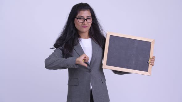 Young Stressed Persian Businesswoman Holding Blackboard and Giving Thumbs Down