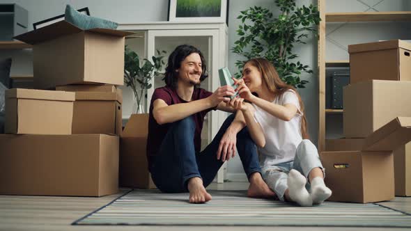 Girl and Guy Unpacking During Relocation Taking Things From Box and Talking