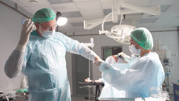 Closeup Nurse Helps Surgeon Wear Medical Gloves Before Surgery