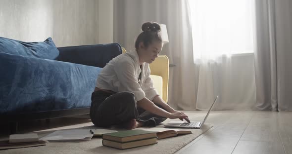 Focused Woman Typing on Laptop and Writing in Notepad