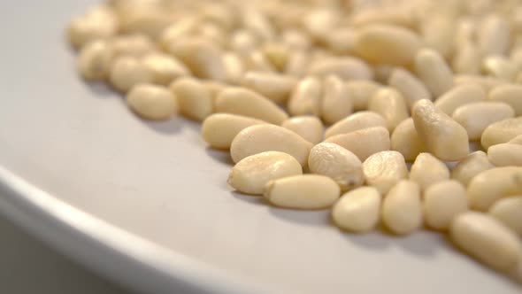 Raw pine nuts. Peeled cedar seeds on beige ceramic plate. Macro