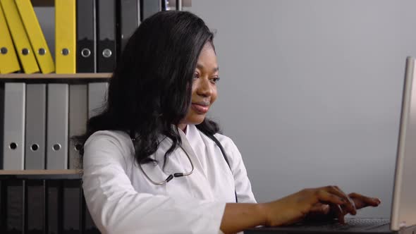 Young African Woman Doctor Works with a Laptop