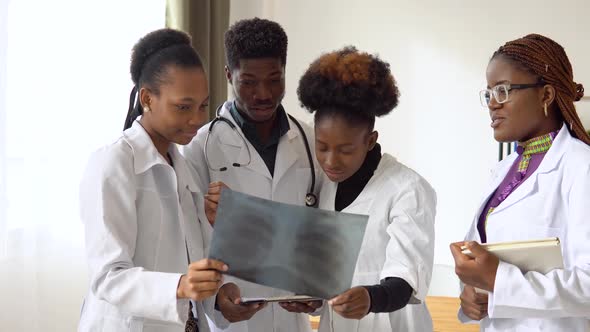 A Group of Four African American Doctors Discuss an Xray Scans of a Patient