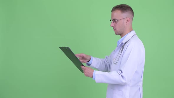 Profile View of Happy Handsome Man Doctor Talking While Holding Clipboard